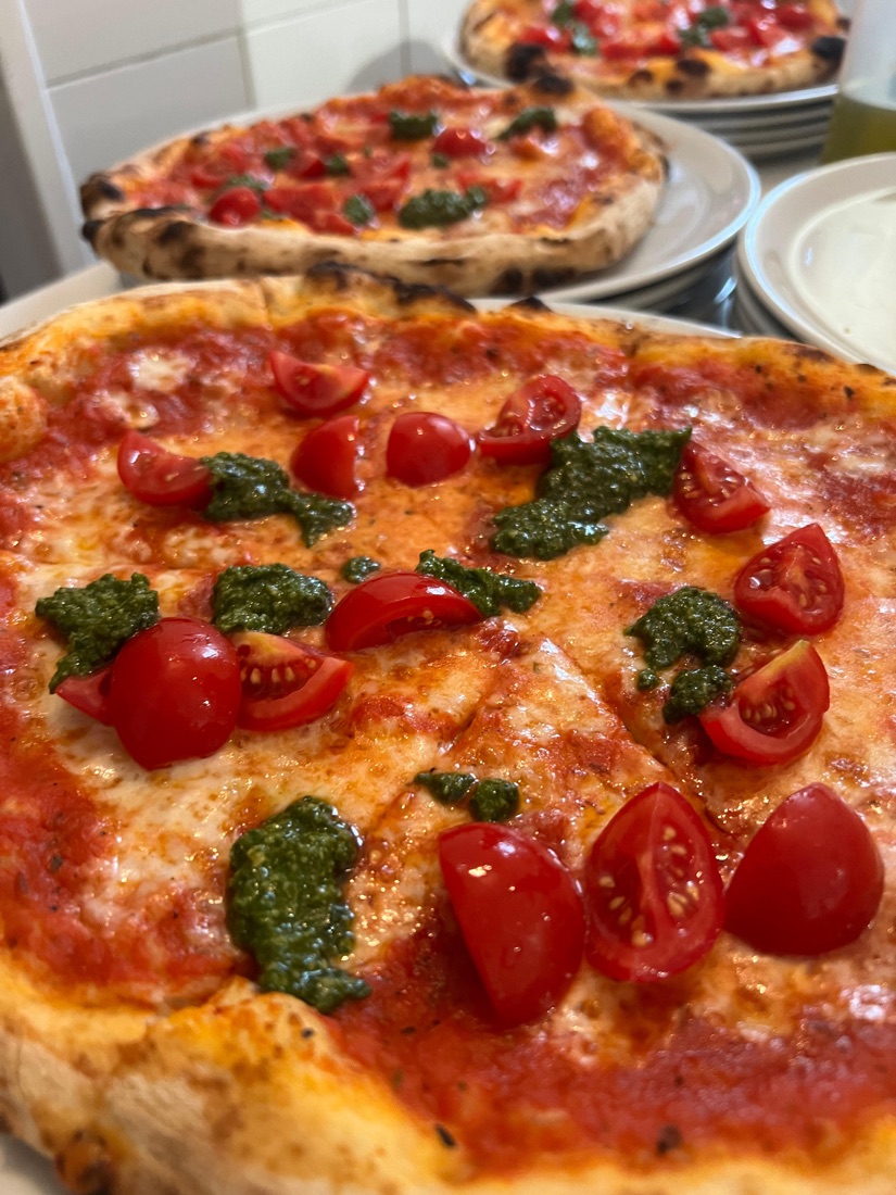 Pizza vegetariana cotta in forno a legna con pomodorini e pesto